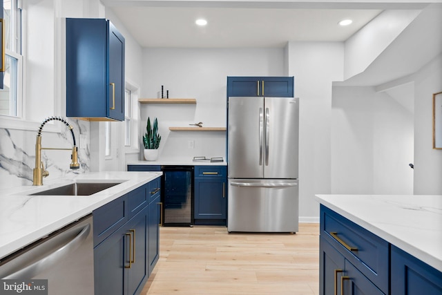 kitchen featuring sink, wine cooler, light wood-type flooring, light stone counters, and stainless steel appliances