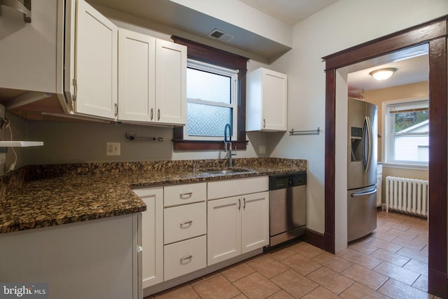 kitchen featuring white cabinetry, sink, radiator heating unit, and stainless steel appliances