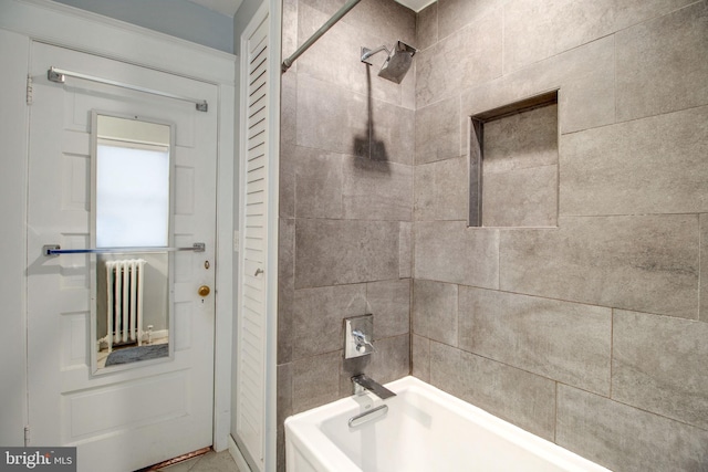 bathroom with radiator heating unit and tiled shower / bath combo