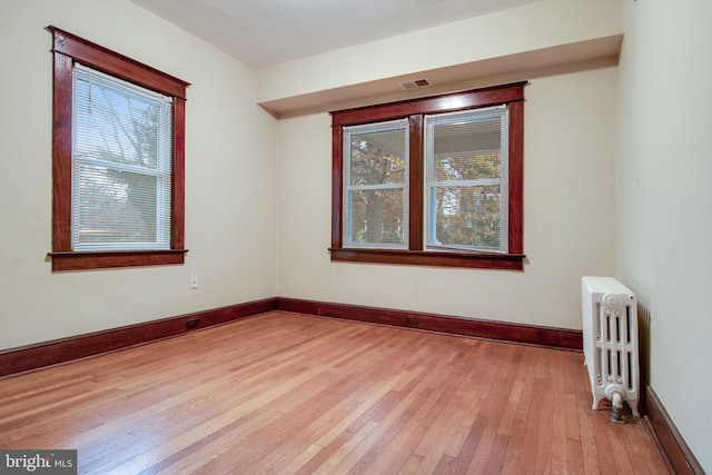 unfurnished room featuring radiator and light hardwood / wood-style floors