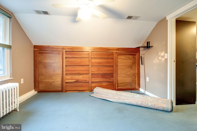 unfurnished bedroom featuring multiple windows, ceiling fan, radiator heating unit, and vaulted ceiling