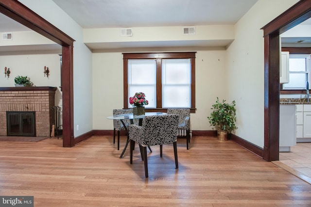 dining area with a brick fireplace and light hardwood / wood-style flooring