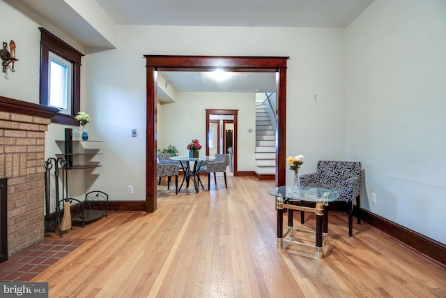 living area with a brick fireplace and light hardwood / wood-style flooring