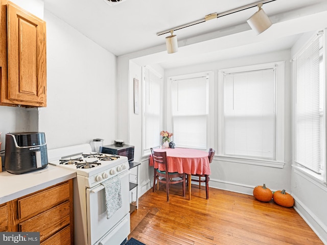 kitchen featuring white gas stove, light hardwood / wood-style floors, and a wealth of natural light