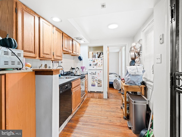 kitchen featuring stainless steel stove, light wood-type flooring, black dishwasher, tasteful backsplash, and white fridge