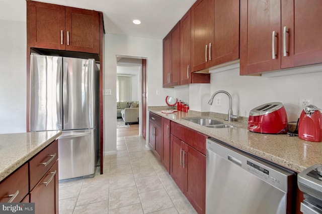 kitchen featuring light stone countertops, light tile patterned floors, stainless steel appliances, and sink