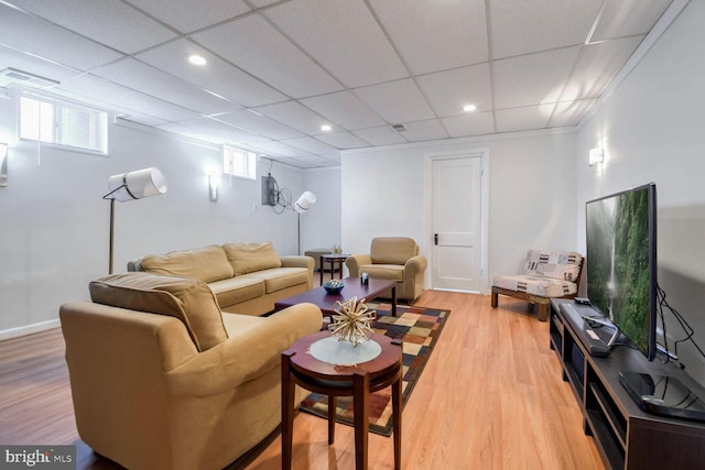 living room with a drop ceiling, wood-type flooring, and ornamental molding