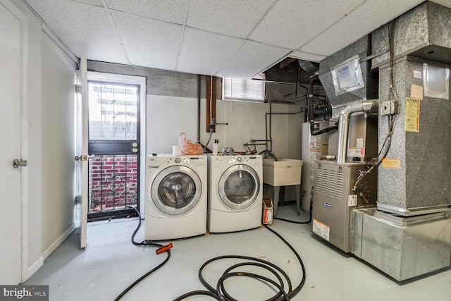 laundry room with washing machine and dryer, heating unit, gas water heater, and sink