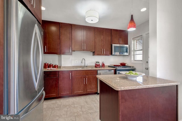 kitchen featuring appliances with stainless steel finishes, light stone counters, sink, light tile patterned floors, and pendant lighting