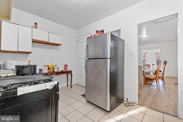 kitchen with stainless steel refrigerator, black range with gas stovetop, white cabinets, and light wood-type flooring