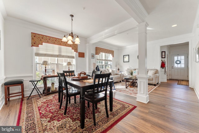 dining area with ornate columns, an inviting chandelier, wood-type flooring, crown molding, and beamed ceiling