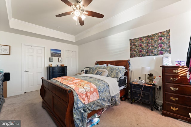 carpeted bedroom featuring ceiling fan, a tray ceiling, and crown molding