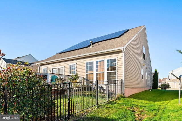 back of house with a lawn and solar panels