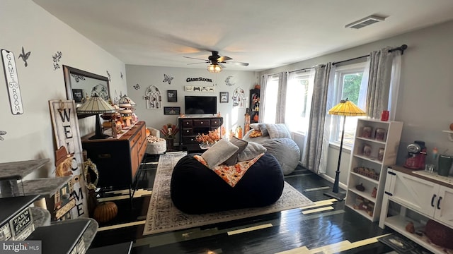 living area featuring wood finished floors, visible vents, and a ceiling fan