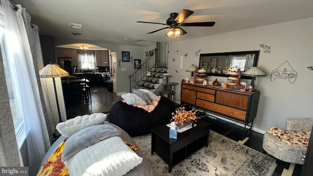 living area featuring arched walkways, wood finished floors, visible vents, baseboards, and stairway