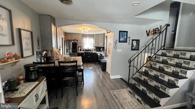 interior space featuring dark wood-type flooring, arched walkways, stairway, and baseboards