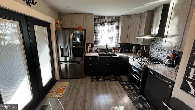 kitchen featuring stainless steel fridge, wood finished floors, wall chimney range hood, double oven range, and a sink