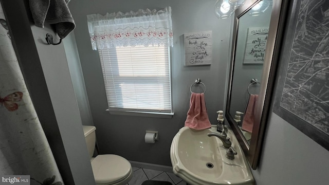 bathroom with toilet, baseboards, and a sink