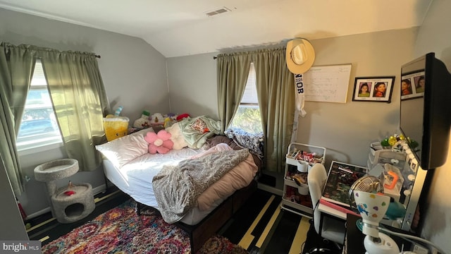 bedroom with lofted ceiling, visible vents, and baseboards