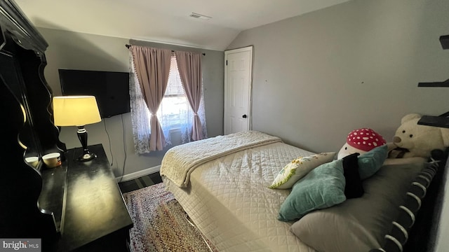 bedroom featuring lofted ceiling, wood finished floors, and visible vents