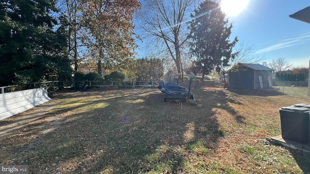 view of yard featuring a storage shed, a fenced backyard, and an outbuilding