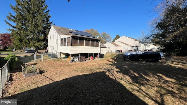 back of house with a sunroom, a fenced backyard, a lawn, and central air condition unit