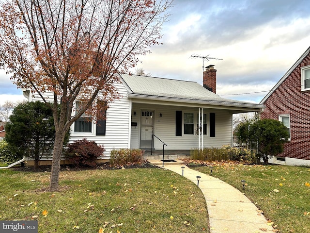 bungalow-style home featuring covered porch and a front yard