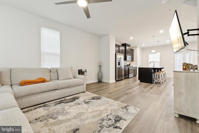 living room with ceiling fan, light hardwood / wood-style flooring, and sink