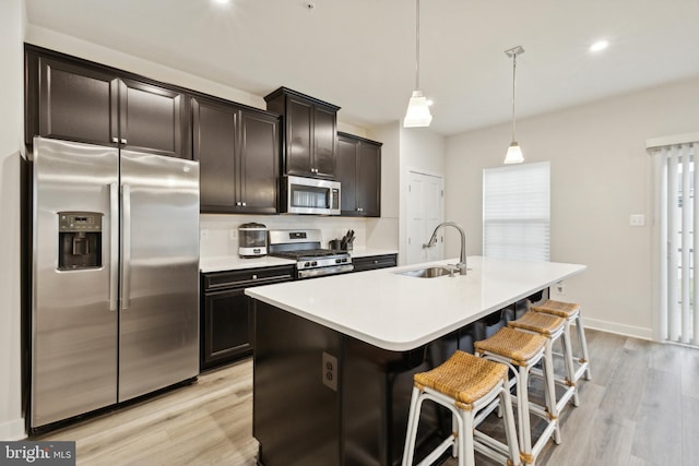 kitchen featuring a wealth of natural light, sink, stainless steel appliances, pendant lighting, and a center island with sink