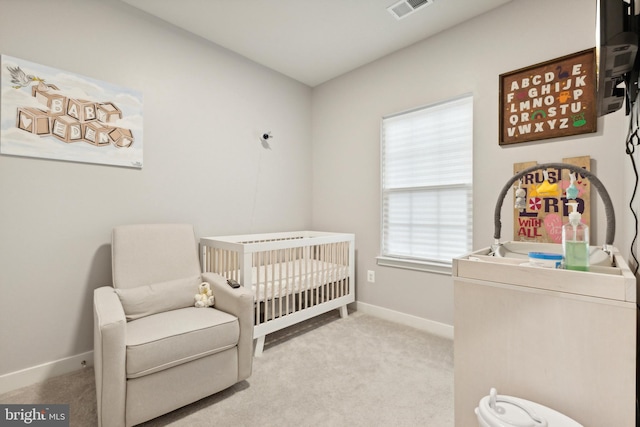 carpeted bedroom featuring multiple windows and a nursery area