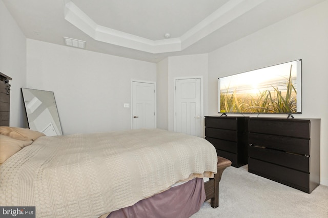 carpeted bedroom with a barn door and a raised ceiling