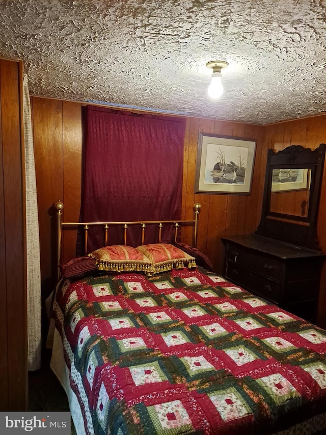 bedroom featuring a textured ceiling and wood walls