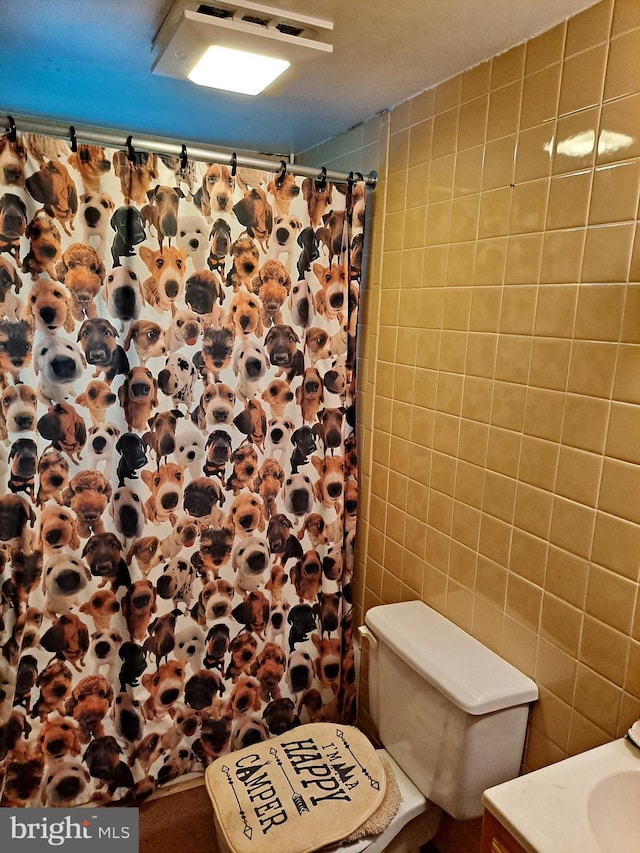 bathroom with vanity, toilet, tile walls, and curtained shower