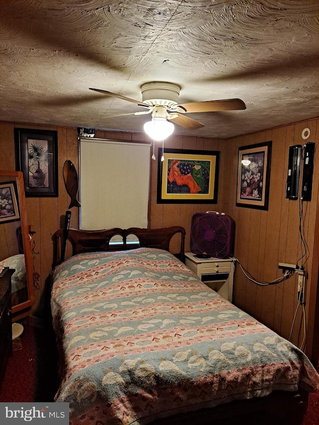 bedroom featuring ceiling fan and wooden walls