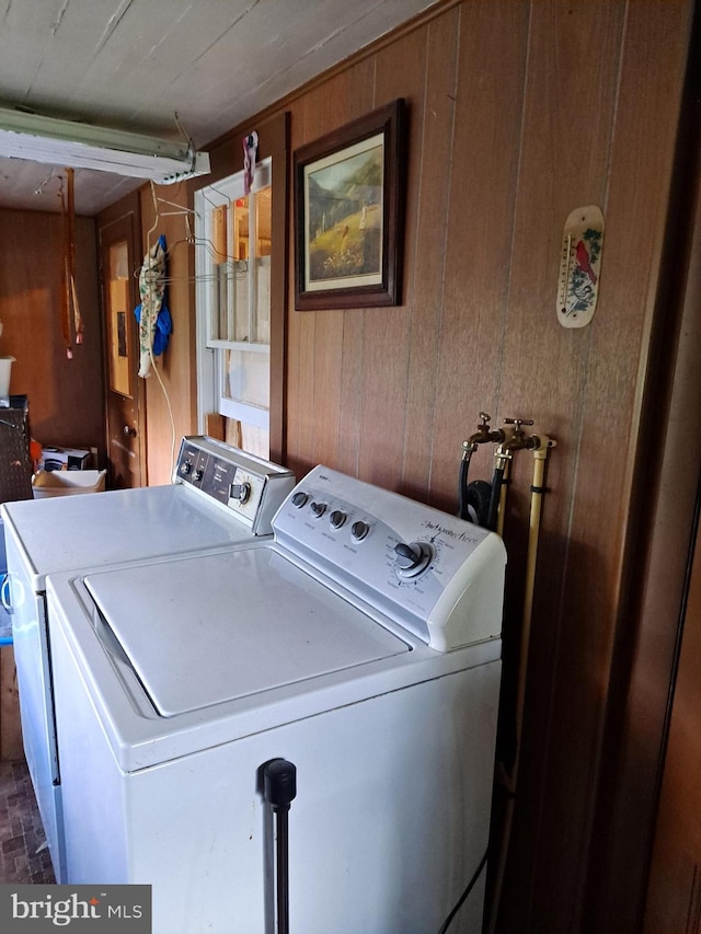 laundry room with washing machine and dryer and wooden walls