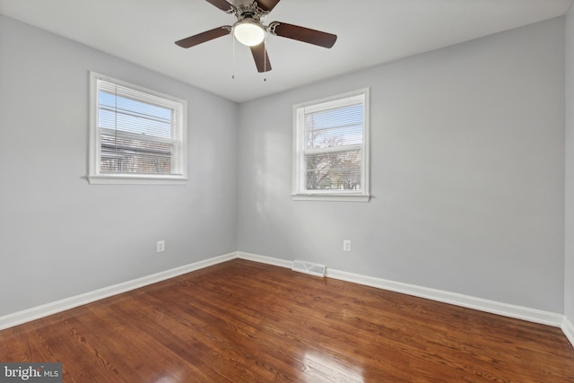 spare room featuring ceiling fan, wood-type flooring, and a wealth of natural light