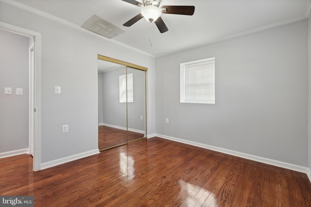 unfurnished bedroom featuring a closet, multiple windows, dark wood-type flooring, and ceiling fan