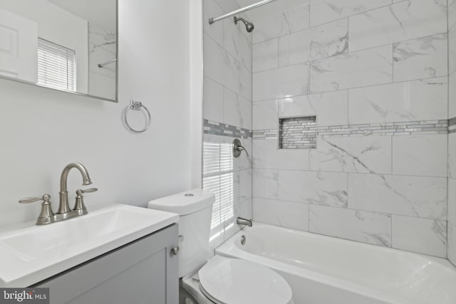 full bathroom featuring vanity, tiled shower / bath combo, and toilet