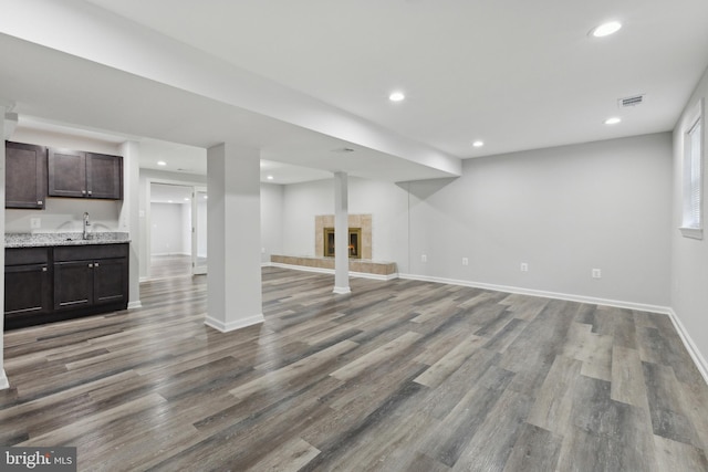 basement with a tile fireplace, sink, and wood-type flooring