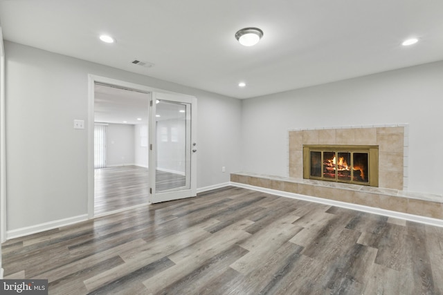 unfurnished room featuring wood-type flooring and a tiled fireplace