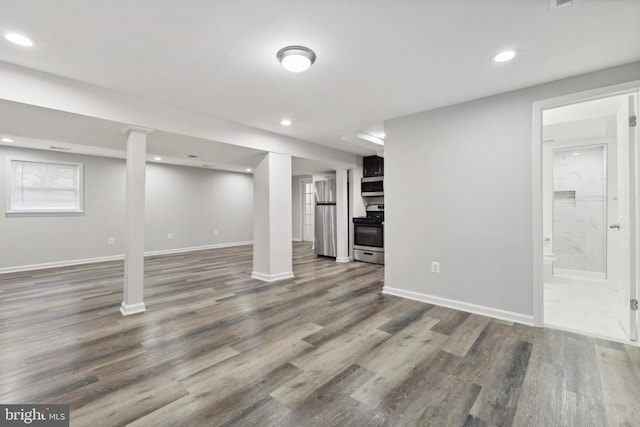 basement featuring stainless steel refrigerator and dark wood-type flooring