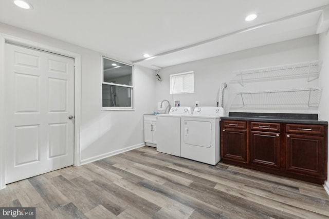 laundry room with washer and clothes dryer, cabinets, and light wood-type flooring