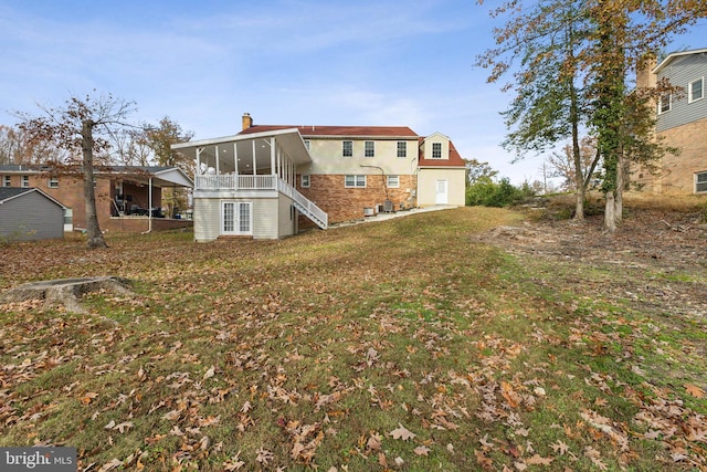 rear view of property with a lawn and a sunroom