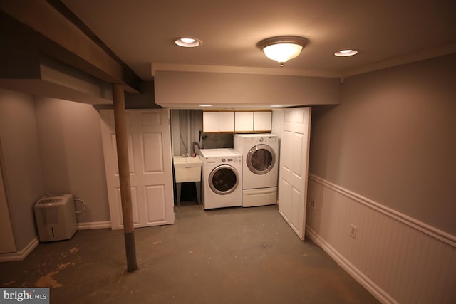 washroom featuring washing machine and clothes dryer, sink, cabinets, and ornamental molding