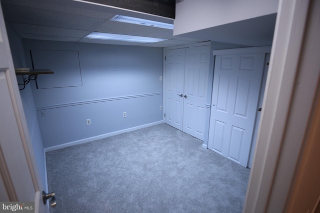 unfurnished bedroom with a paneled ceiling, carpet floors, and a closet