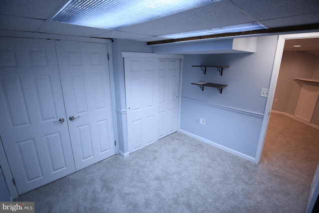 basement featuring a drop ceiling and light colored carpet