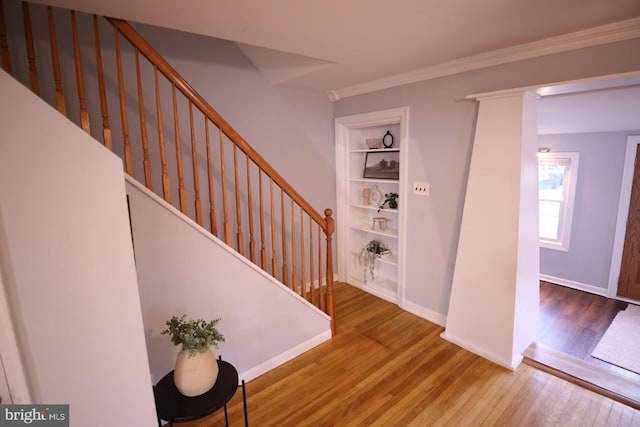 stairs with built in shelves, wood-type flooring, and ornamental molding