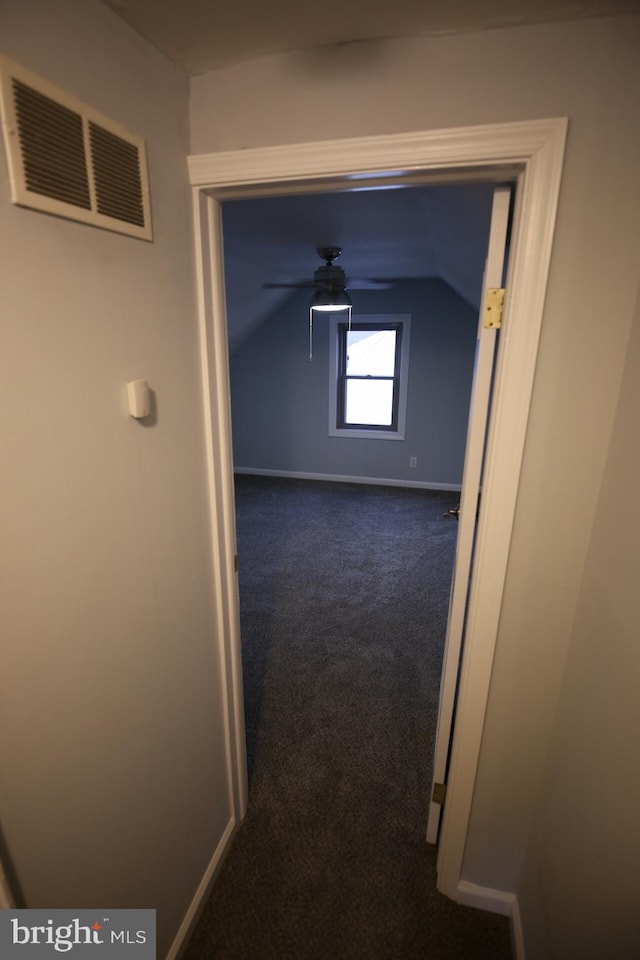 corridor with dark carpet and lofted ceiling