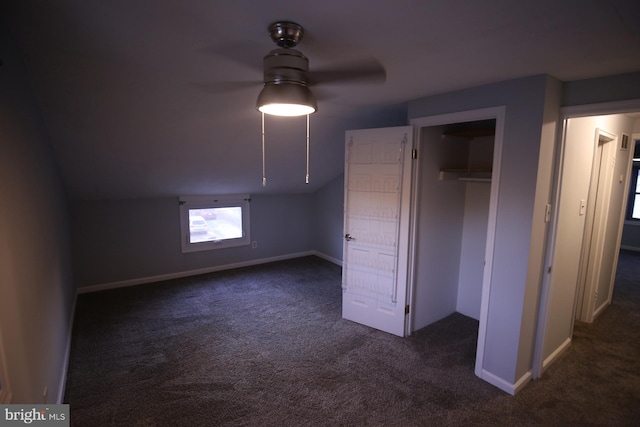 bonus room with dark colored carpet and lofted ceiling