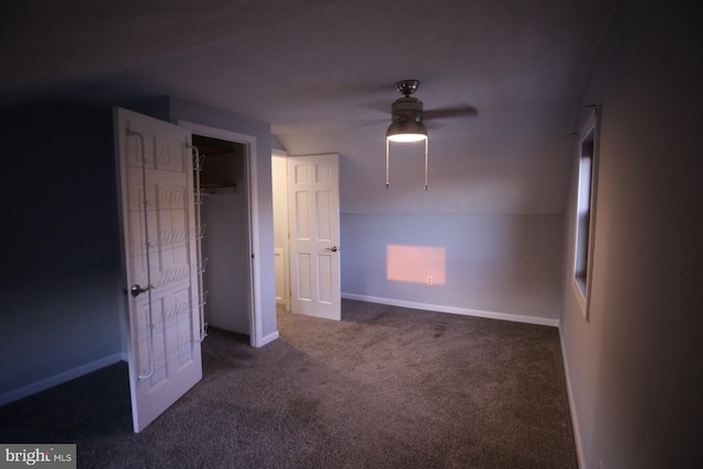 unfurnished bedroom featuring ceiling fan, dark carpet, and lofted ceiling